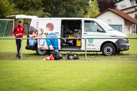 Trainer, der Trainingsmaterialien aus dem Kofferraum des DFB Mobils holt.