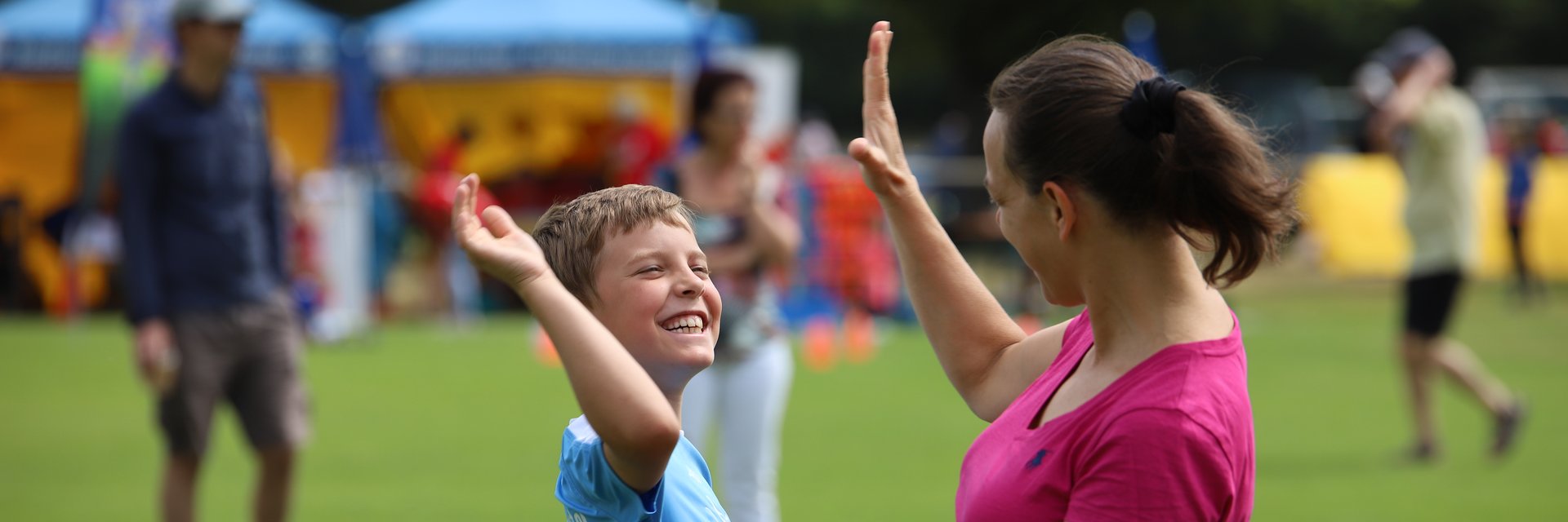Ein Junge, der bei seiner Mutter abklatscht und sie anlächelt. 