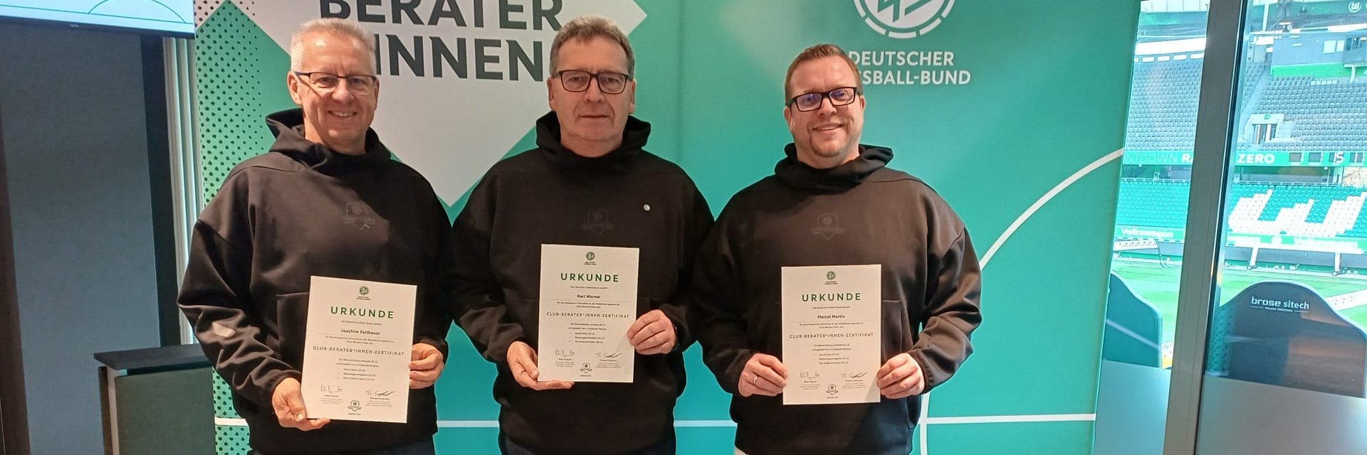 Die drei Club-Berater des Badischen Fußballverbandes. Sie stehen in schwarz gekleidet und mit Urkunden in der Hand, vor einer Fotowand.