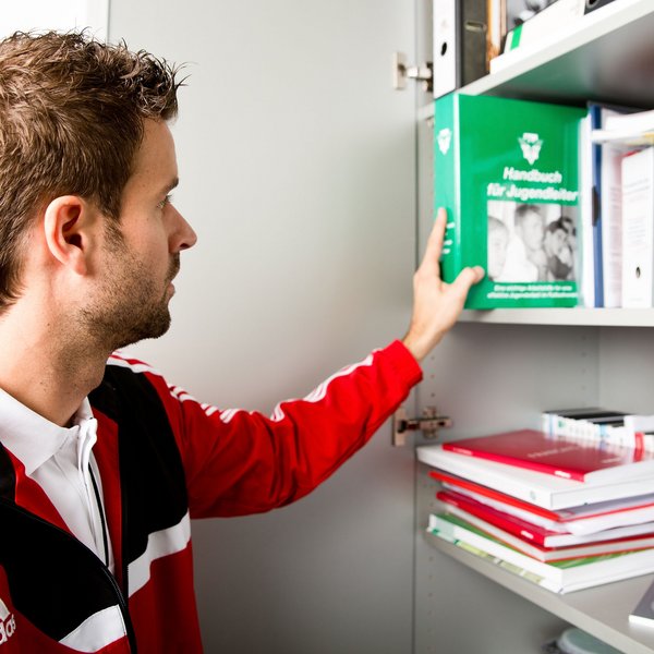 Ein Vereinsmitarbeiter, der ein Buch in ein Regal einräumt.