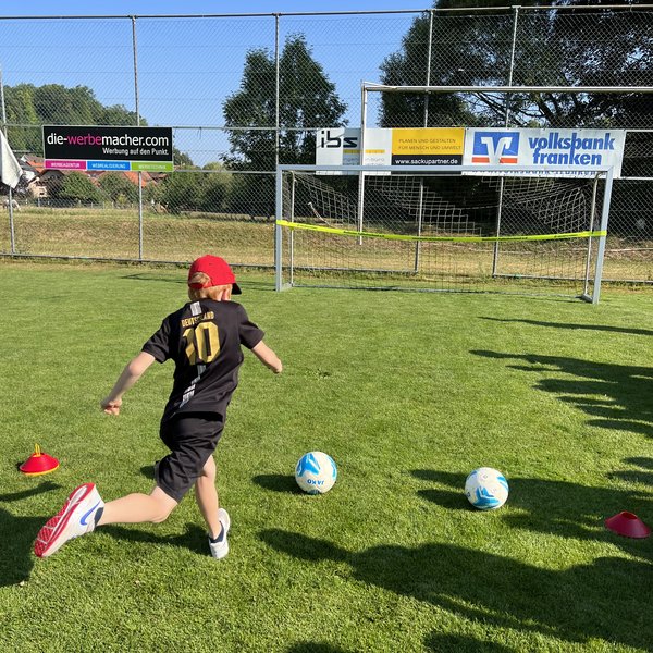 Ein Junge, der auf einem Fußballplatz zum Torschuss anläuft.