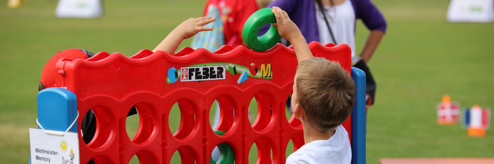 Ein Junge, der einen Ring in ein großes 4-Gewinnt-Spiel einwirft.
