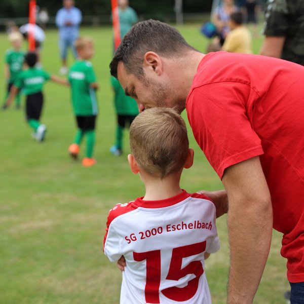 Ein Trainer und sein junger Spieler von hinten, sie unterhalten sich.