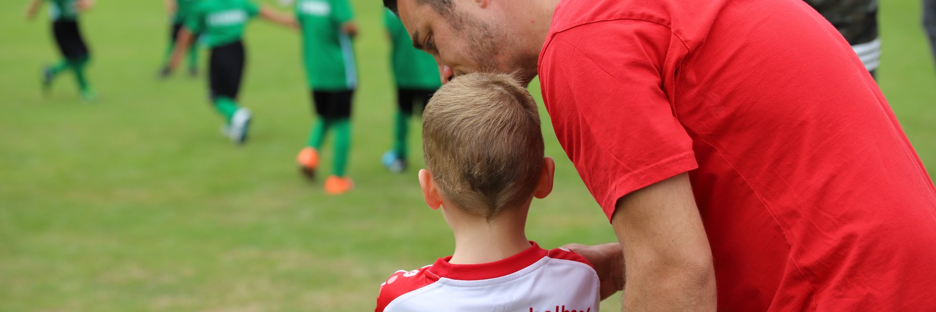 Ein Trainer und sein junger Spieler von hinten, sie unterhalten sich.