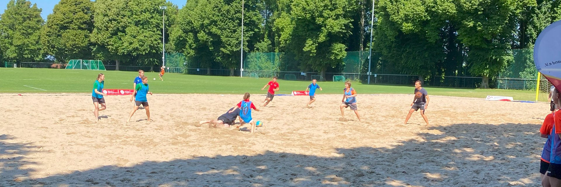 Spieler*innen, die im Sand auf der Sportschule Schöneck Beachsoccer spielen. 