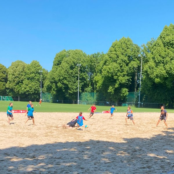 Spieler*innen, die im Sand auf der Sportschule Schöneck Beachsoccer spielen. 