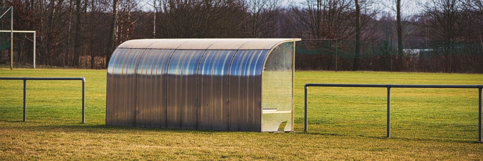 Eine Auswechselbank mit einem Fußballplatz im Hintergrund.