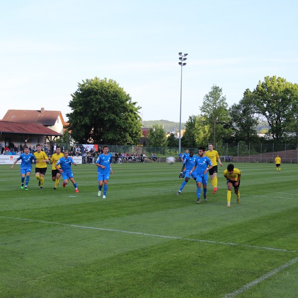 Eine Spielsituation aus einem Juniorenspiel. Eine Mannschaft in blau und eine in gelb spielen gegeneinander. Der Ball wurde von einem Spieler nach außen weggeschossen.