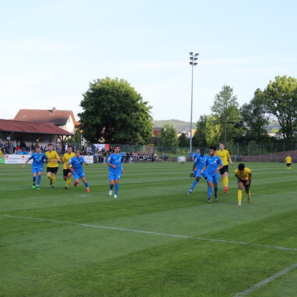 Eine Spielsituation aus einem Juniorenspiel. Eine Mannschaft in blau und eine in gelb spielen gegeneinander. Der Ball wurde von einem Spieler nach außen weggeschossen.